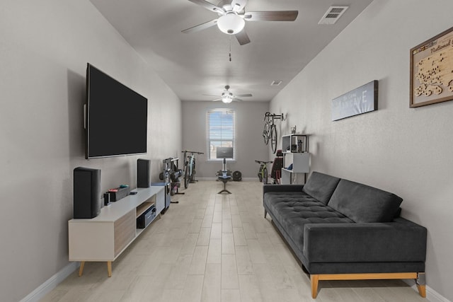 living area featuring light wood-type flooring, visible vents, ceiling fan, and baseboards