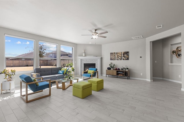 living area featuring baseboards, visible vents, a ceiling fan, light wood-type flooring, and a fireplace