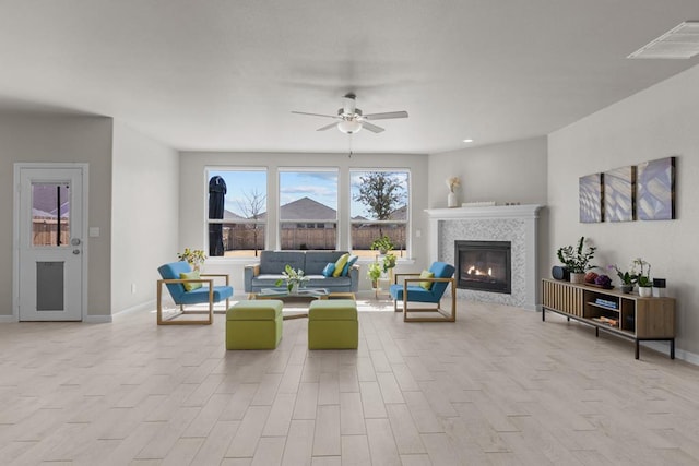 living area with baseboards, visible vents, ceiling fan, wood finished floors, and a fireplace