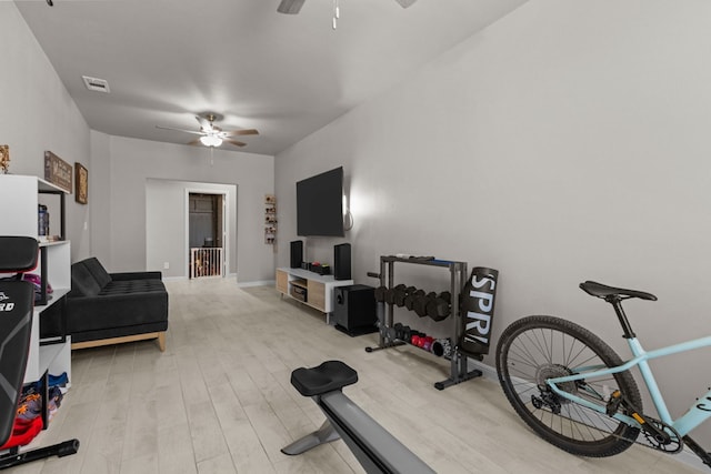 workout area featuring baseboards, light wood-style flooring, visible vents, and a ceiling fan