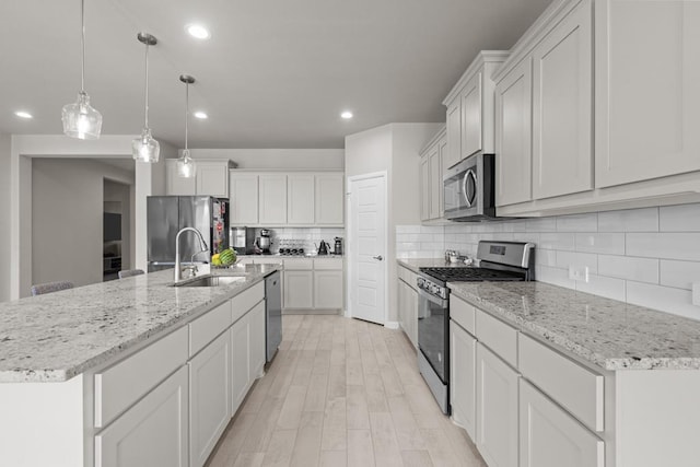 kitchen featuring decorative backsplash, appliances with stainless steel finishes, light wood-style floors, white cabinets, and a sink