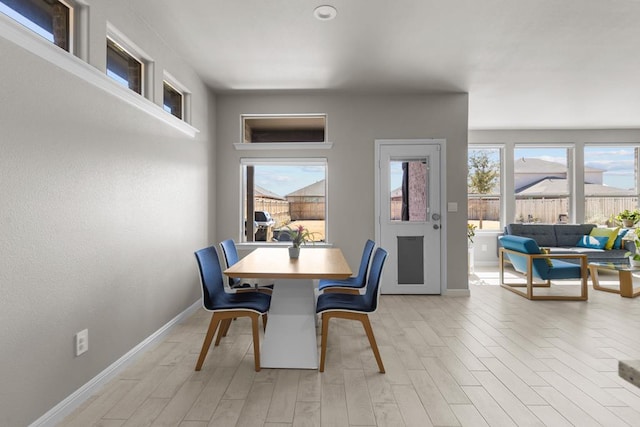 dining area with light wood-type flooring and baseboards