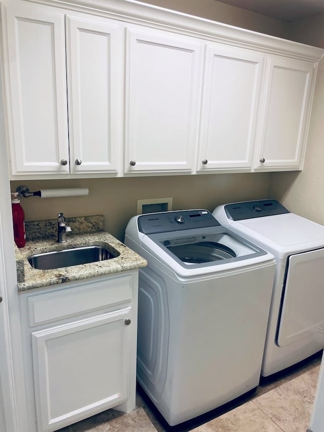 laundry room featuring light tile patterned flooring, cabinet space, a sink, and separate washer and dryer