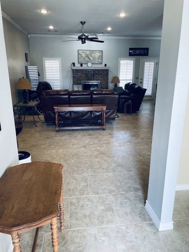 living room with a healthy amount of sunlight, a fireplace, ornamental molding, and a ceiling fan