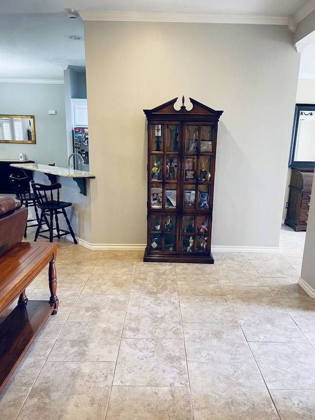 interior space featuring crown molding, baseboards, and light tile patterned floors