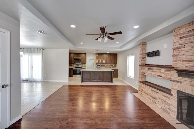 1901 College Ave, Midland, TX 79701 - unfurnished living room with a fireplace, a tray ceiling, healthy amount of natural light, a ceiling fan, and recessed lighting