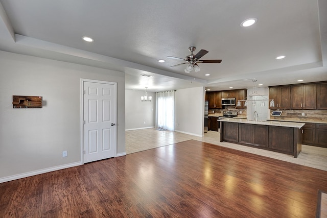 1901 College Ave, Midland, TX 79701 - unfurnished living room featuring a ceiling fan, baseboards, recessed lighting, light wood-style floors, and a tray ceiling