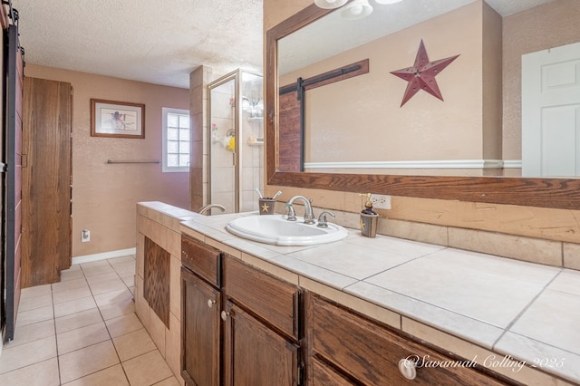 bathroom with tile patterned flooring, vanity, a textured ceiling, and walk in shower