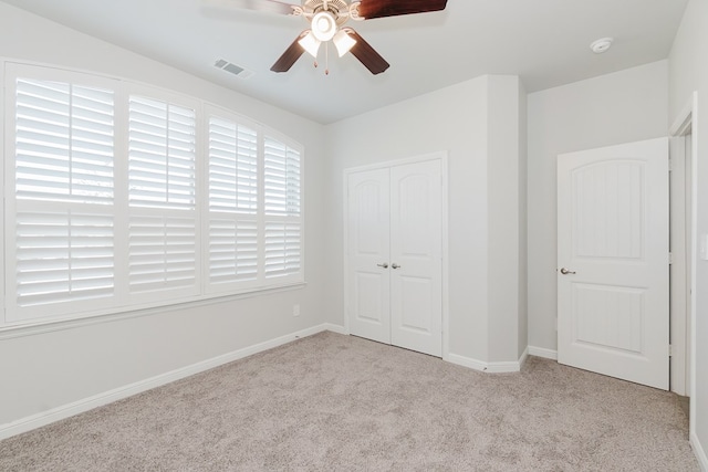 unfurnished bedroom with ceiling fan, light carpet, and a closet