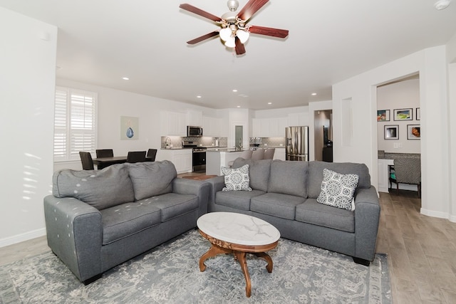 living room featuring ceiling fan and light hardwood / wood-style floors