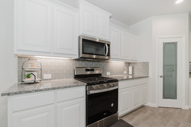 kitchen featuring light stone countertops, white cabinetry, stainless steel appliances, tasteful backsplash, and light wood-type flooring