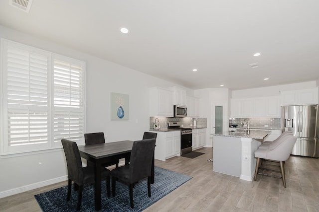 dining space with light hardwood / wood-style floors, plenty of natural light, and sink