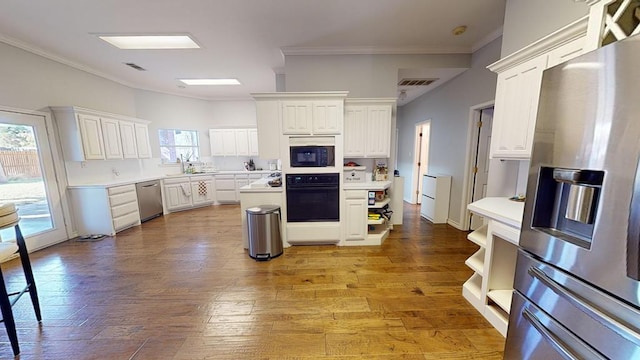 kitchen featuring light hardwood / wood-style flooring, white cabinetry, a healthy amount of sunlight, and black appliances