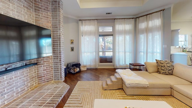 living room with hardwood / wood-style floors, ornamental molding, and brick wall