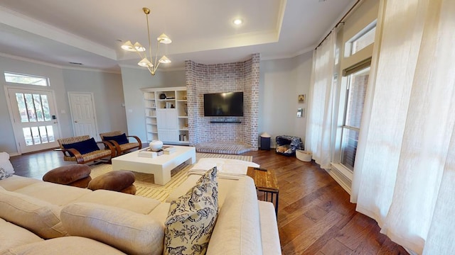 living room featuring ornamental molding, dark hardwood / wood-style floors, a raised ceiling, and a notable chandelier