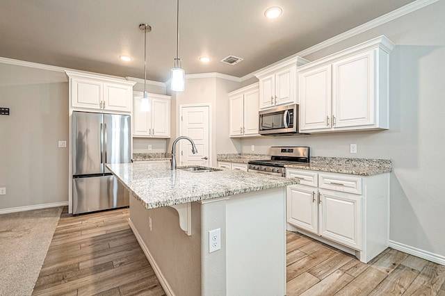 kitchen with a kitchen island with sink, white cabinets, sink, light stone counters, and stainless steel appliances