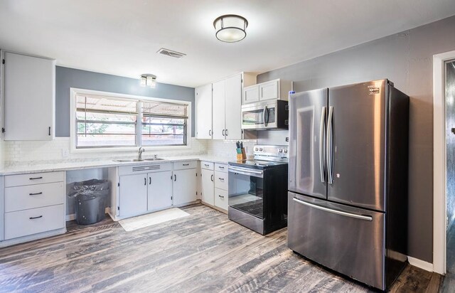 702 Dellwood St, Midland, TX 79701 - kitchen featuring stainless steel appliances, a sink, light countertops, decorative backsplash, and wood finished floors