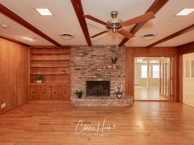 3307 Stanolind Ct, Midland, TX 79707 - unfurnished living room with beam ceiling, wood walls, a ceiling fan, wood finished floors, and a brick fireplace