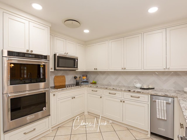 3307 Stanolind Ct, Midland, TX 79707 - kitchen featuring appliances with stainless steel finishes, tasteful backsplash, light tile patterned flooring, white cabinets, and recessed lighting