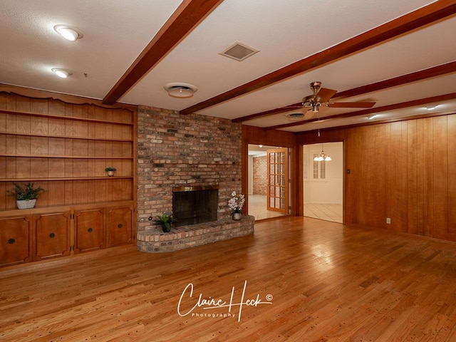 3307 Stanolind Ct, Midland, TX 79707 - unfurnished living room featuring beam ceiling, a ceiling fan, wood walls, wood finished floors, and a brick fireplace