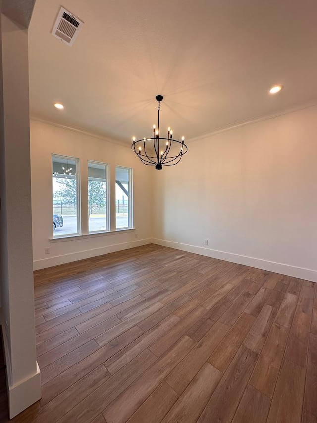 unfurnished dining area featuring wood-type flooring, ornamental molding, and a chandelier