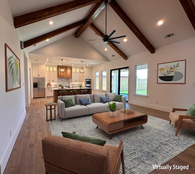 living room with beam ceiling, sink, light hardwood / wood-style flooring, high vaulted ceiling, and ceiling fan with notable chandelier