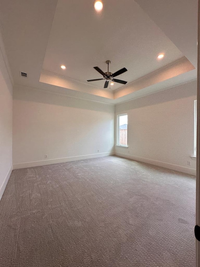 empty room with carpet, a raised ceiling, and ceiling fan