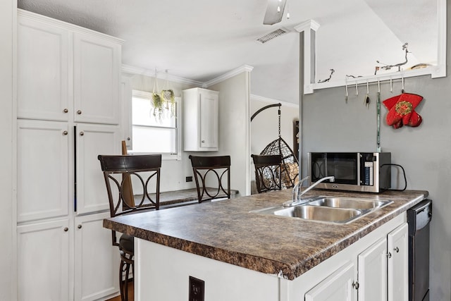 kitchen featuring visible vents, dark countertops, stainless steel microwave, white cabinetry, and a sink