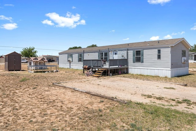 rear view of house with an outdoor structure, dirt driveway, a wooden deck, a shed, and a trampoline