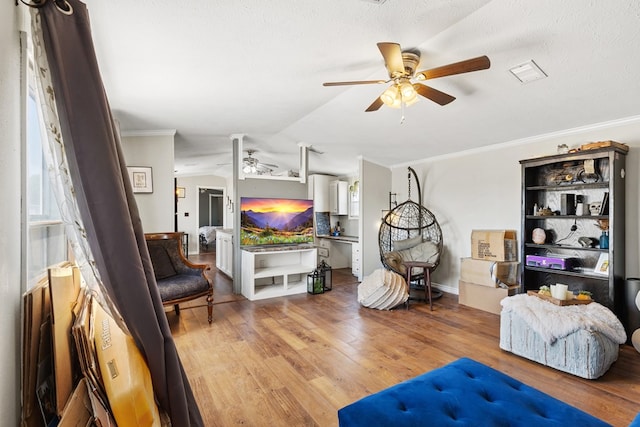 sitting room featuring visible vents, lofted ceiling, light wood-style flooring, ceiling fan, and crown molding