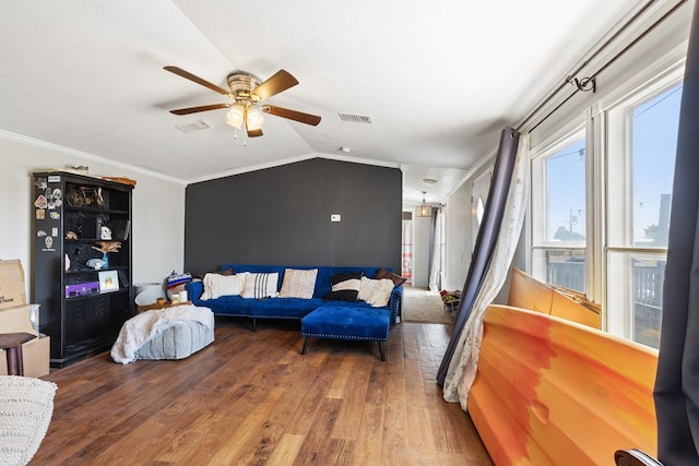 living area featuring lofted ceiling, crown molding, visible vents, and wood finished floors