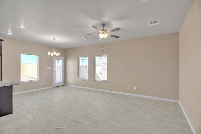 spare room featuring ceiling fan with notable chandelier