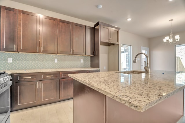 kitchen with a wealth of natural light, light stone countertops, sink, and pendant lighting