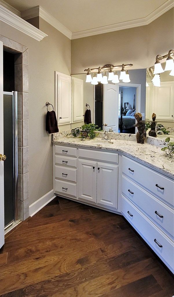 bathroom featuring vanity, a shower with shower door, ornamental molding, and hardwood / wood-style flooring