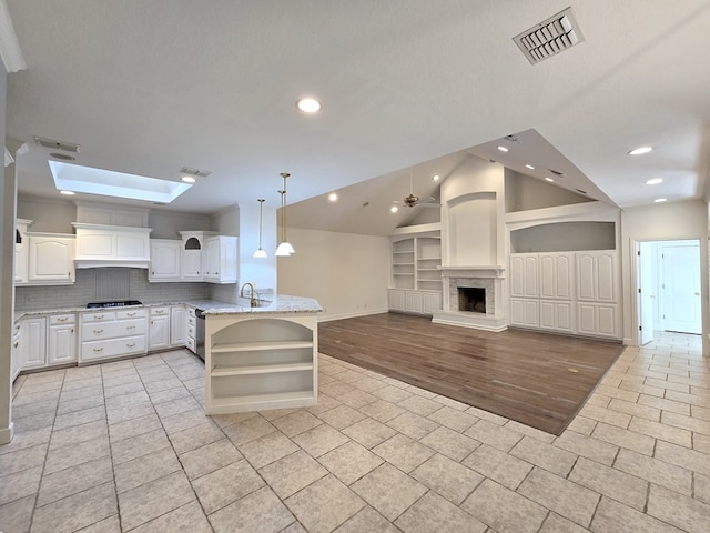 kitchen featuring light stone countertops, decorative light fixtures, gas stovetop, white cabinetry, and ceiling fan