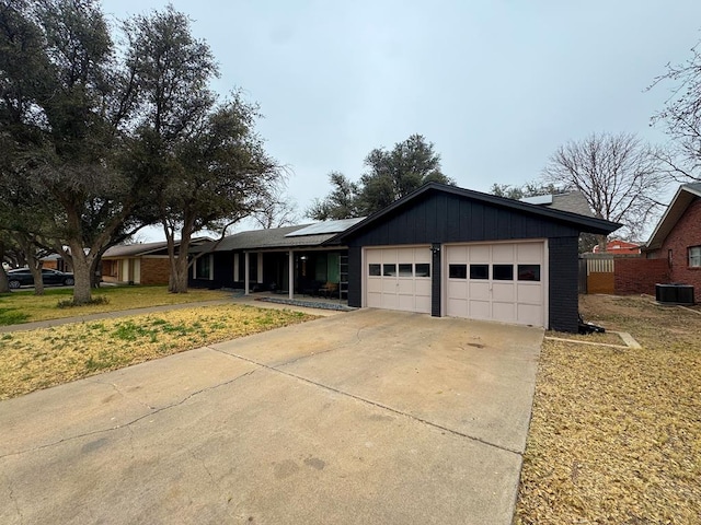 single story home with cooling unit, a garage, and solar panels