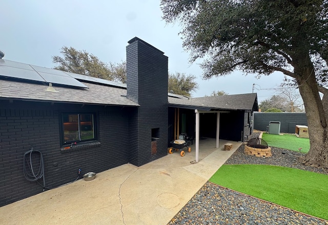 rear view of property with solar panels, central AC, a patio area, and an outdoor fire pit