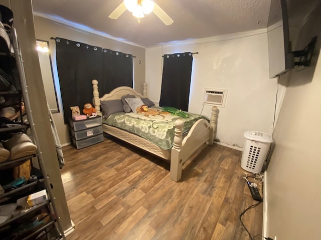 bedroom featuring hardwood / wood-style floors, a wall unit AC, ceiling fan, and ornamental molding