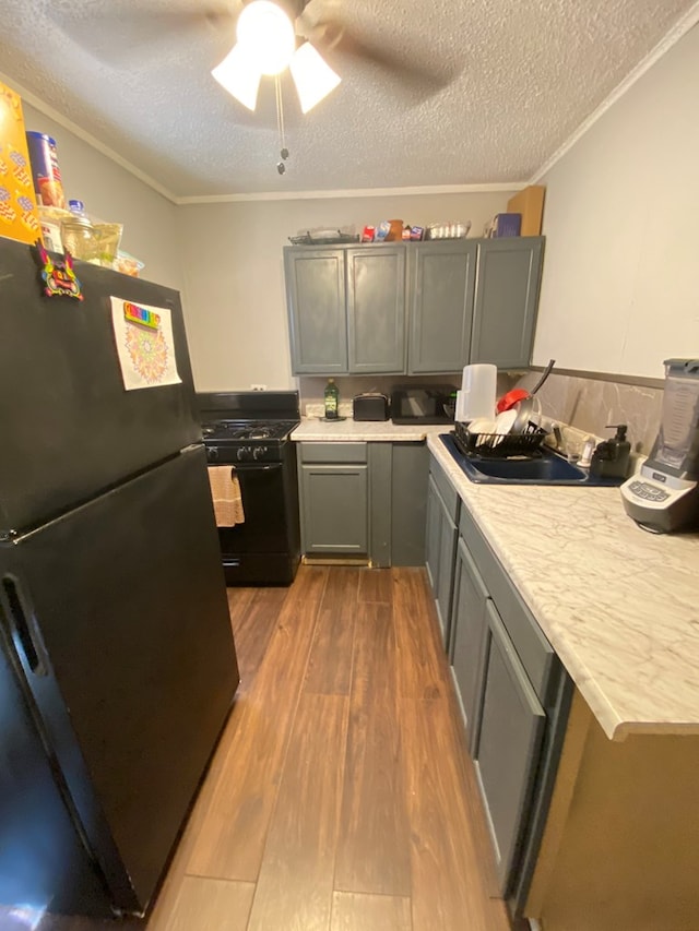 kitchen featuring black appliances, light hardwood / wood-style floors, gray cabinetry, and a textured ceiling