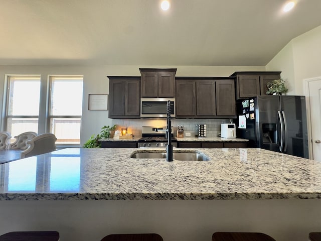 6005 Scaled Quail Rd, Midland, TX 79707 - kitchen with stainless steel microwave, refrigerator with ice dispenser, backsplash, dark brown cabinetry, and a sink