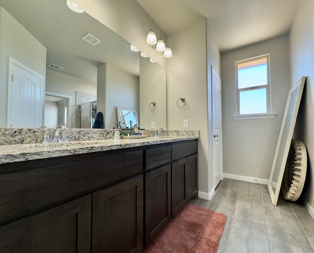 6005 Scaled Quail Rd, Midland, TX 79707 - bathroom featuring wood finished floors, a stall shower, double vanity, and baseboards