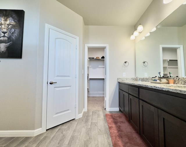 6005 Scaled Quail Rd, Midland, TX 79707 - full bath with wood finished floors, double vanity, a spacious closet, and baseboards