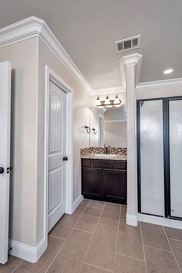 bathroom featuring tile patterned floors, vanity, a shower with shower door, and ornamental molding