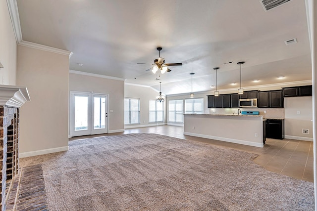 unfurnished living room with a fireplace, light tile patterned floors, ceiling fan with notable chandelier, and crown molding