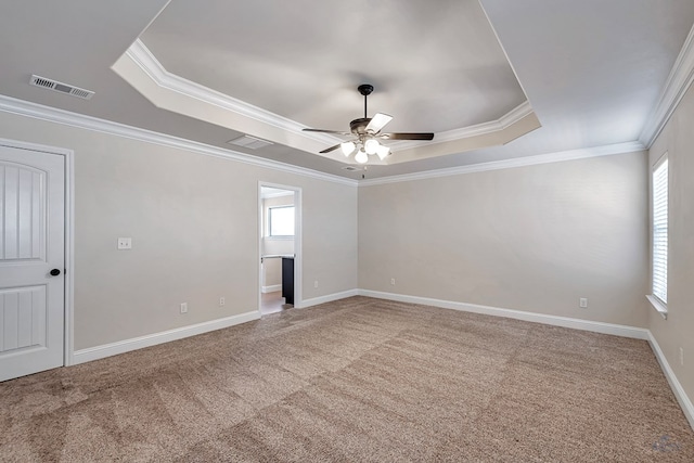 carpeted empty room with ceiling fan, crown molding, and a tray ceiling