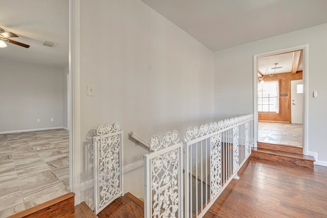 corridor featuring baseboards, visible vents, wood finished floors, and an upstairs landing