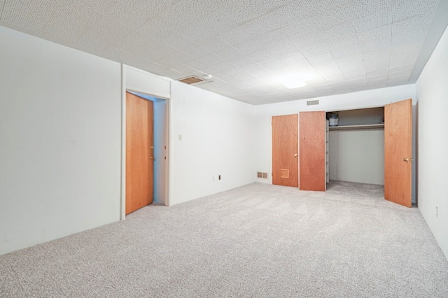 unfurnished bedroom with light carpet, a closet, and visible vents