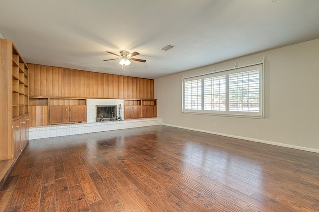 unfurnished living room featuring dark wood-type flooring, a fireplace, visible vents, baseboards, and a ceiling fan