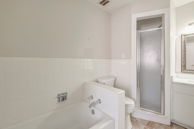 bathroom with visible vents, toilet, a garden tub, vanity, and tile walls