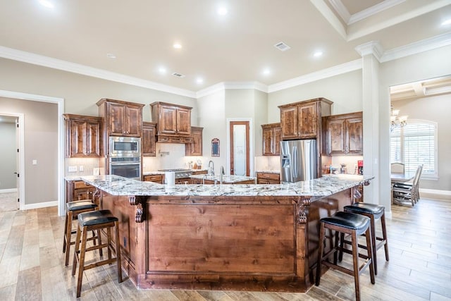 7311 E County Rd 112, Midland, TX 79706 - kitchen with appliances with stainless steel finishes, a large island, a kitchen breakfast bar, light stone countertops, and backsplash